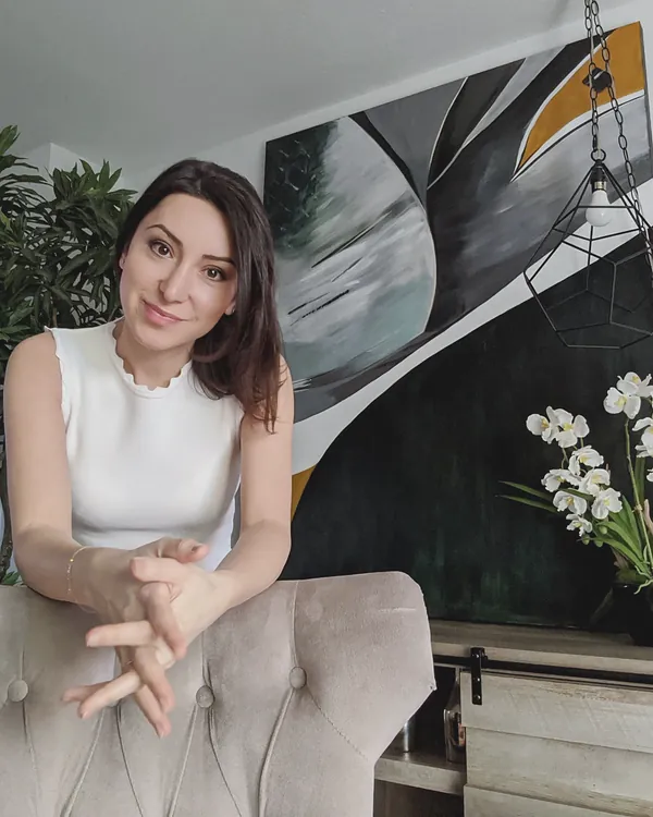 Ayka Ramazanova at home in front of one of her large abstract paintings