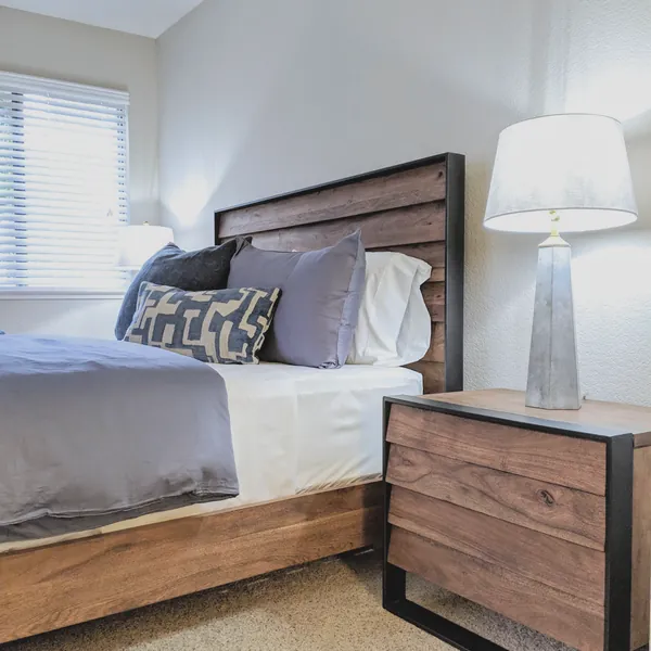 Bedroom with chevron bedding, a reclaimed wood nightstand, mercury glass lamp and abstract brushstroke art