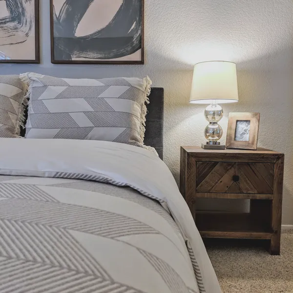 Bedroom with a sculptural wood dresser, steel-framed bed and large framed tree artwork
