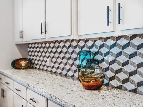 Kitchen detail with a geometric marble and wood backsplash and hand-blown glass vases