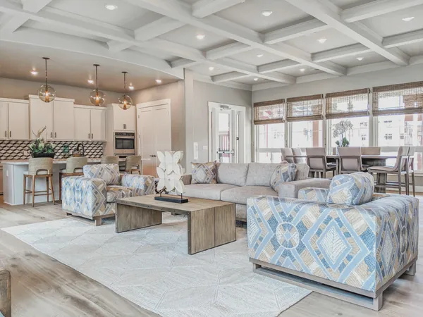 Open great room with patterned armchairs, a reclaimed wood coffee table, kitchen and dining area beyond