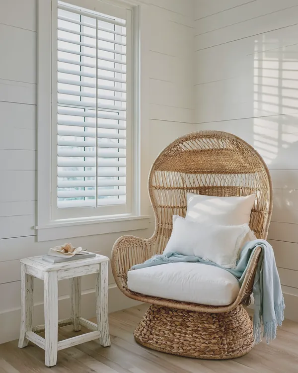 Design rendering of a coastal reading corner with a rattan chair, white shiplap and plantation shutters